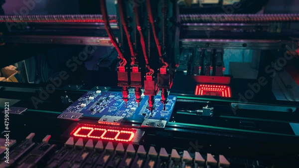 Fototapeta Pick and Place robot machine: SMD Assembly of electronic components on a motherboard by an automated Pick and Place robot. Technology for SMD assemblage of chips with artificial intelligence.