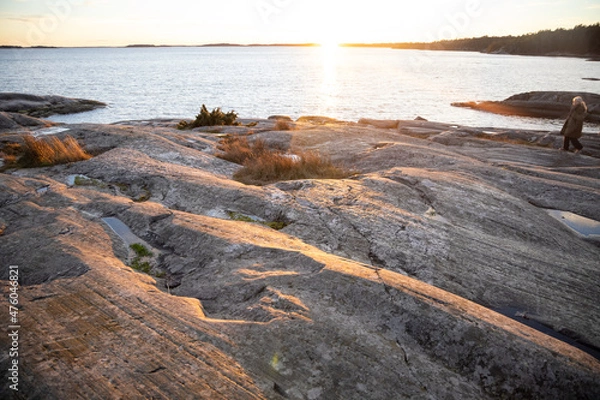 Obraz People walking on a rocky shore in Bjorno nature reserve at Baltic sea. Beautiful natural Scandinavian landscape on Sunny late autumn or winter day in Sweden, Stockholm archipelago 2021.12.17