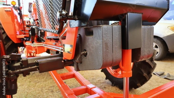 Fototapeta Tractor weight set. Metal counterweights are mounted in front of the tractor to balance the weight on the ground background. Selective focus