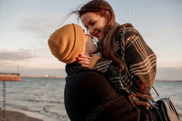 Obraz Young beautiful couple on a walk by the sea in autumn in the off-season, hugging, walking, smiling