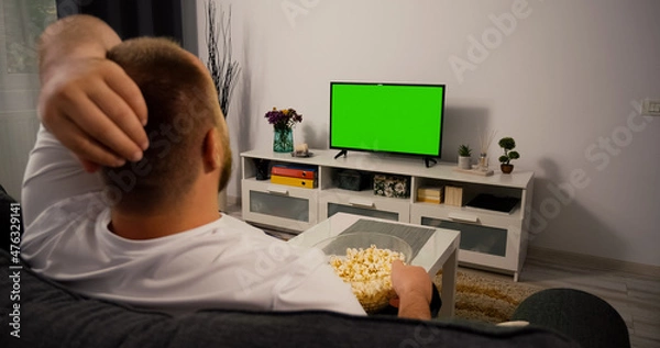 Fototapeta Watching Green Screen Chroma Key TV at home interior. Man Watches a Sport Match. Support favorite Football Rugby Team.