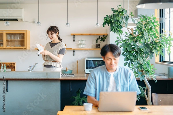 Fototapeta テレワークする男性とキッチンにいる女性（笑顔）

