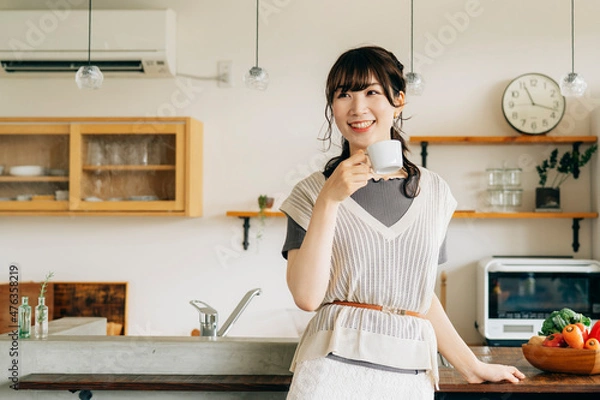 Fototapeta キッチンの前でホットドリンクを飲む女性
