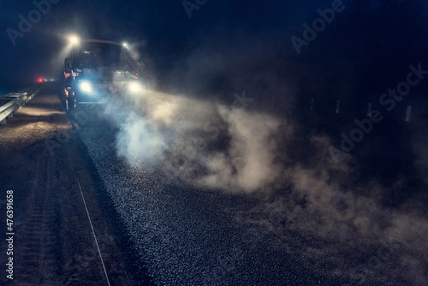 Fototapeta Rolling asphalt at night with headlights. Road construction.