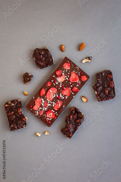 Fototapeta top view of quality craft chocolate bar, freeze-dried strawberry's chocolate bar among nut's chocolate pieces