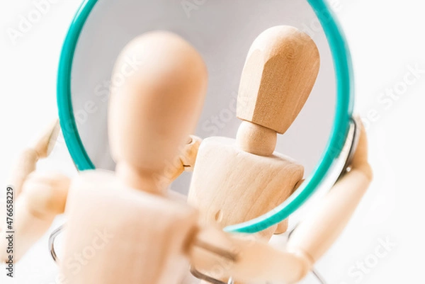 Fototapeta Wooden dummy looks at its reflection in the mirror