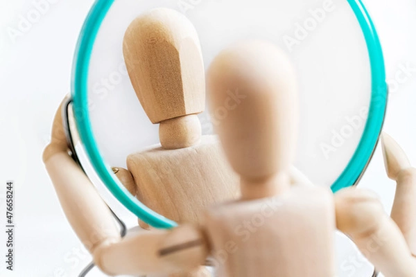 Fototapeta Wooden dummy looks at its reflection in the mirror