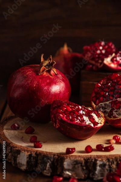 Fototapeta Red ripe pomegranates on a wooden background. The cut fruits of the pomegranate tree.