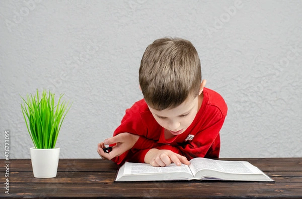 Fototapeta The boy is European. Read book. Open Bible book, on the table.