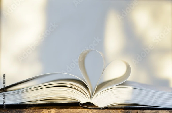 Fototapeta he open book lies on the table. The pages are folded in the shape of a heart. Concept of love for literature