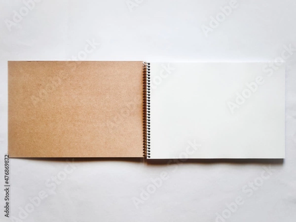 Fototapeta 螺旋綴じの茶色いスケッチブックの見開き。茶色い表紙の裏と白い画用紙。灰色背景で真上から撮影。