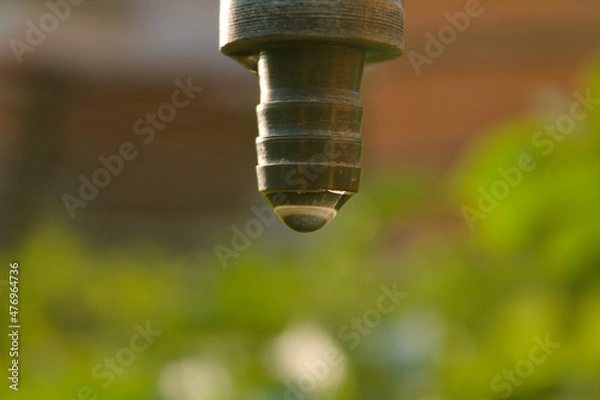 Fototapeta closeup of faucet with water droplet and green in background which describe good agriculture.