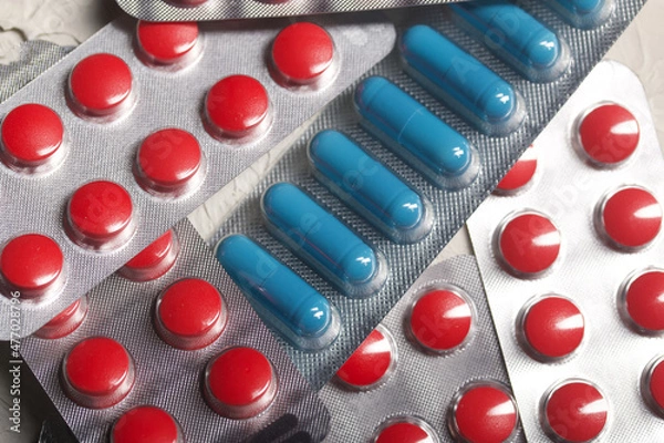 Fototapeta Blisters with red and blue tablets. On a light background. Close-up.