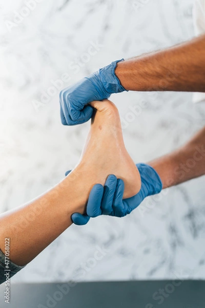 Obraz Close up of a podiatrist hands with medical gloves exploring the foot of a patient in the podiatry clinic.