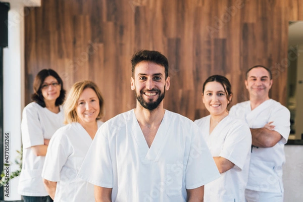 Fototapeta Chiropodists team doctors looking at camera and smiling in medical center with white medical gown.