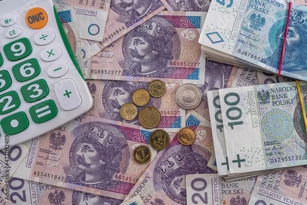 Fototapeta  new clean smooth Polish zloty banknotes are scattered and it's time for a new calculator.