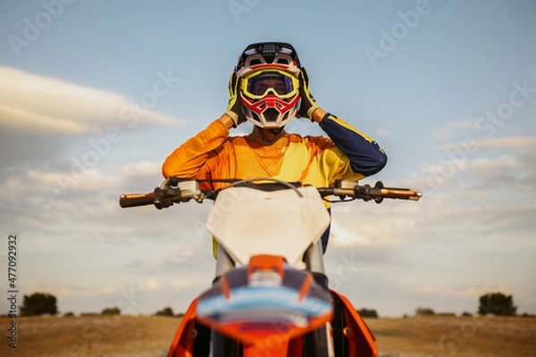 Obraz Portrait of motocross rider taking off helmet