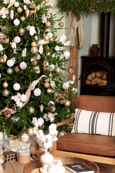 Fototapeta Interior decorated for Christmas. New Year's gifts, in warm colors. Christmas tree by the fireplace.