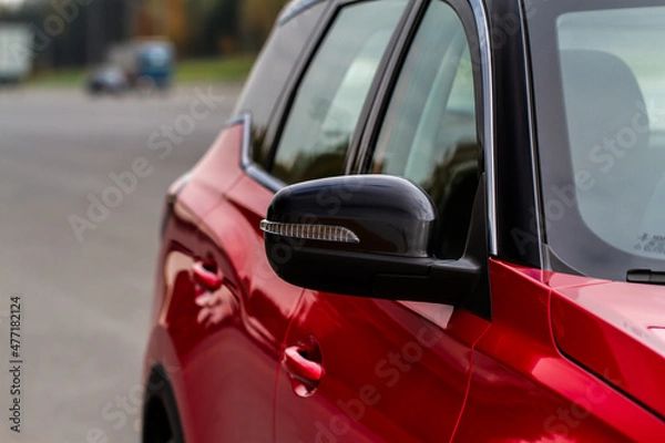 Fototapeta Close up front view of car side mirror. Front rear view mirror on the car window. Car exterior details. Red car mirror.