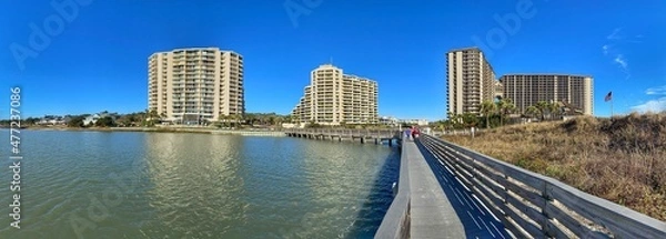 Fototapeta Waterfront scene of the wooden boardwalk path and the luxury resort buildings in North Myrtle Beach, South Carolina. Picture taken on Christmas Day, 2021