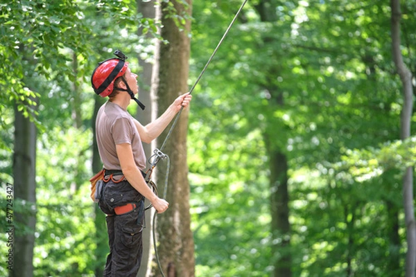 Fototapeta Man belays his partner climber with belaying device and rope. Climber's handsman holding equipment for rock mountaineering security.