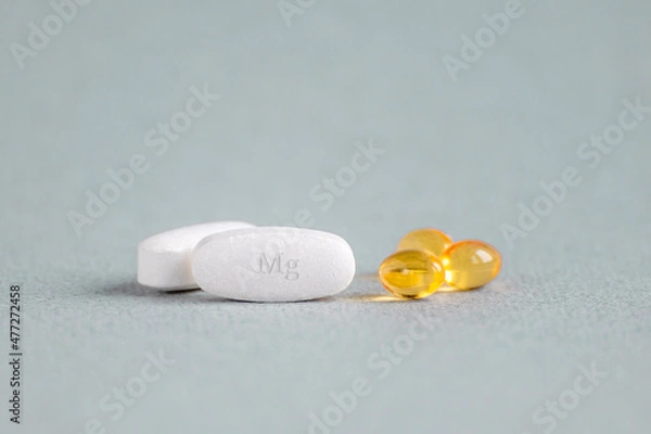 Fototapeta A complex of Mg ( magnesia, magnesium ) and vitamin D ( omega 3 ) capsules for treatment and human health on a light background. Copy space.