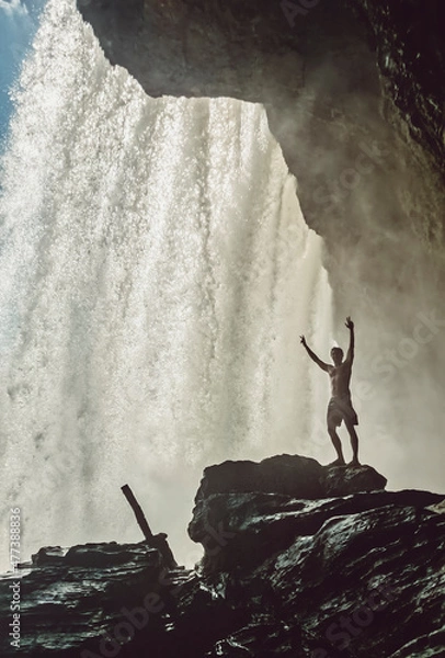 Fototapeta Fitness guy standing in front of a waterfall in Chapada das Mesas National Park, in Brazil