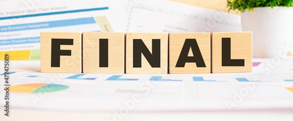 Fototapeta FINAL word on wooden cubes. The background is a business graphs. Business and finance concept