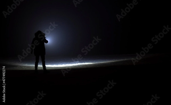 Obraz man with flashlight in winter night