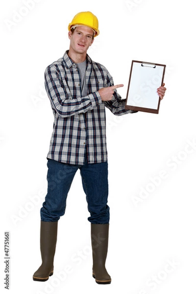 Obraz Construction worker pointing to a blank clipboard