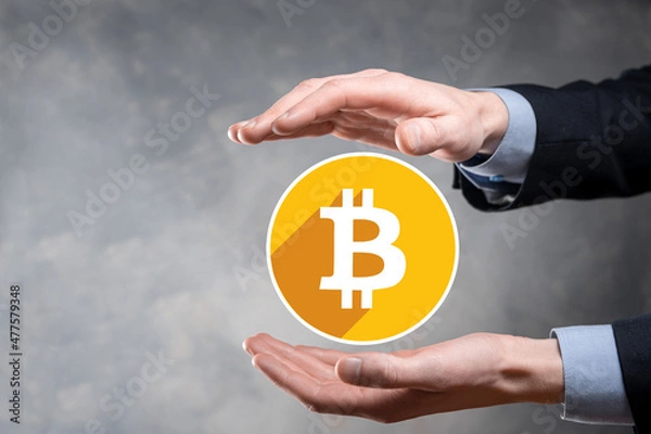 Fototapeta Male hand holding a bitcoin icon on grey background. Bitcoin Cryptocurrency Digital Bit Coin BTC Currency Technology Business Internet Concept