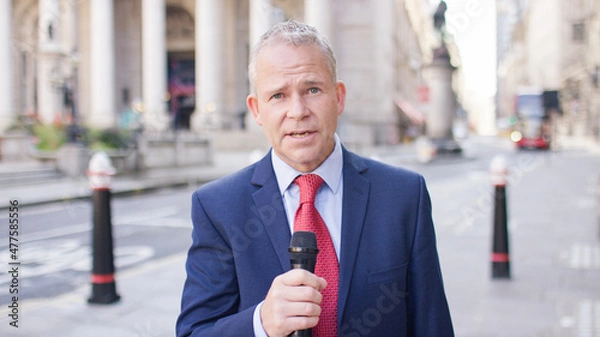Fototapeta Portrait of news reporter reporting to camera in the street