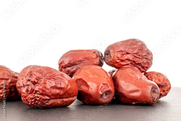 Fototapeta Several sweet dried ziziphus berries on a slate stone, close-up, isolated on white.