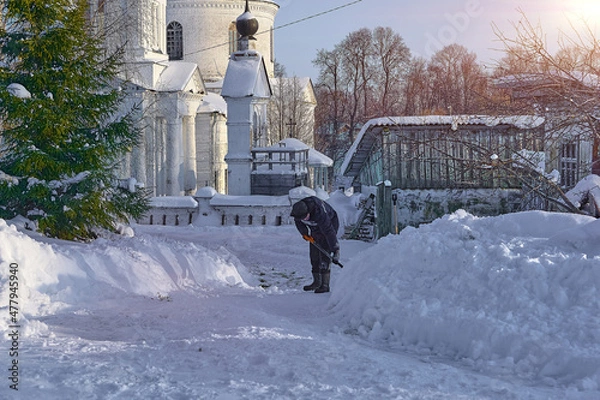 Obraz уборка снега лопатой. мужчина убирает снег на улице во дворе