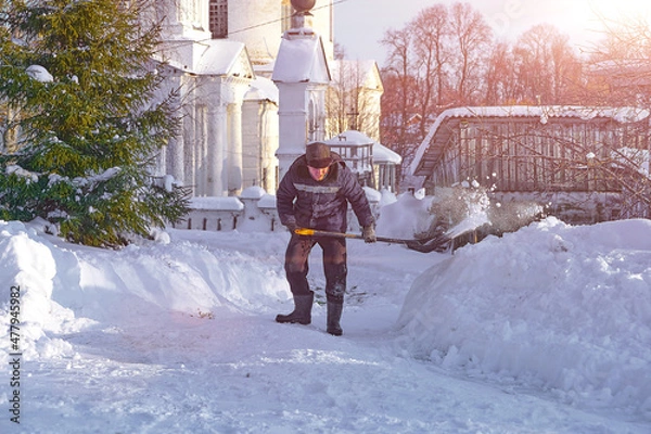 Obraz уборка снега лопатой. мужчина убирает снег на улице во дворе