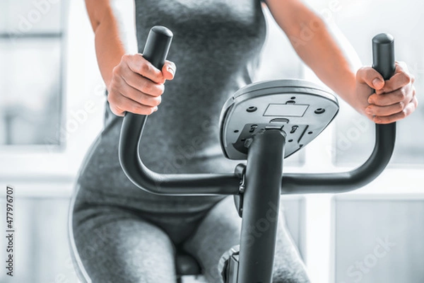 Fototapeta The girl is engaged in an exercise bike, the concept of doing sports, burning excess weight, rehabilitation or recovery after injuries.