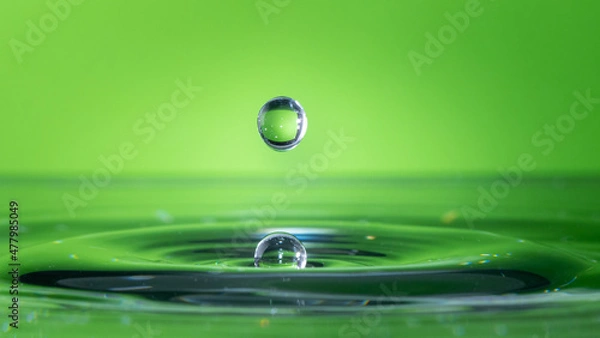 Obraz Water drop falling and impacting body of water.