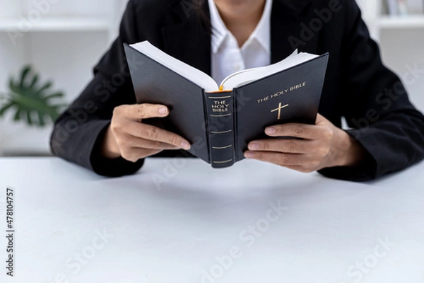 Obraz A person is reading the Bible, he is praying to the Bible, he is reading and studying the Bible. Concept of Christianity and Bible Study.
