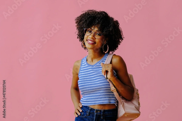 Obraz beautiful smiling girl in eyeglasses with backpack posing on pink background, back to school concept