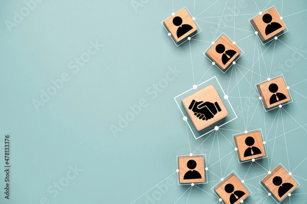 Fototapeta Top view design on blue background of Hand shaking which print screen on wooden cube block which connection with human icon for business deal and agreement concept.