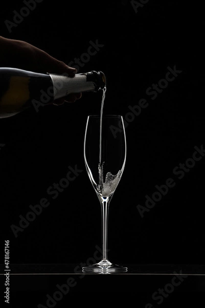 Obraz Pouring champagne in glass graphically presented in studio setting