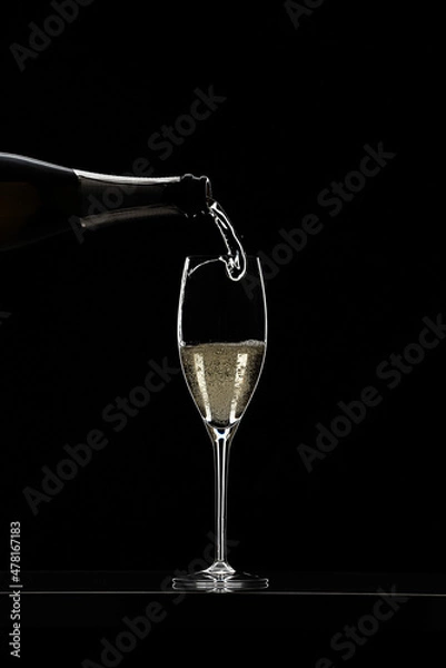 Obraz Pouring champagne in glass graphically presented in studio setting