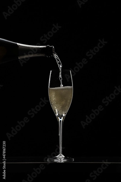 Obraz Pouring champagne in glass graphically presented in studio setting