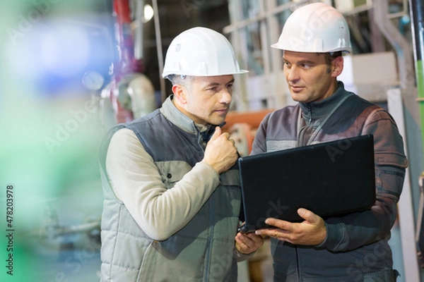 Fototapeta workers with hardhat on looking at the laptop screen