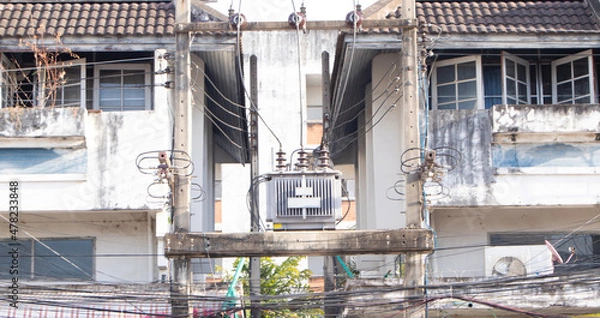 Fototapeta Transformers  big size and electric wire. Electrical post. Technology on electric power. Transformers and phone lines against buildings as a background copy space. Energy and technology. .
