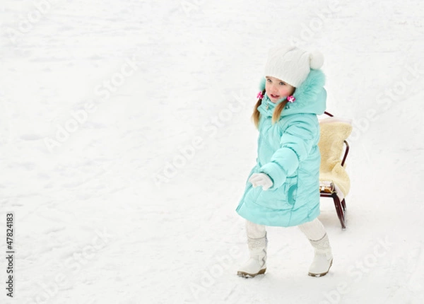 Fototapeta Little girl pulling her sledge in winter day