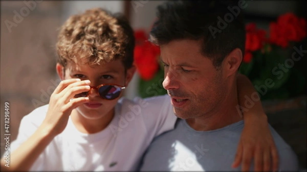Fototapeta Candid child with father together, small boy wearing sunglasses with arm around dad