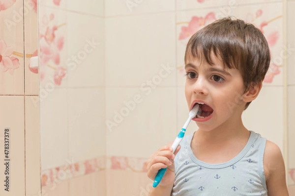 Obraz The boy brushes his teeth with a toothbrush.