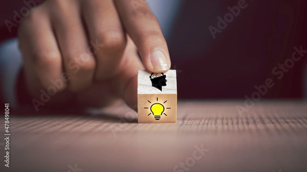 Fototapeta Problem solving, new ideas, creativity, teamwork, and innovation concepts. Person hand flips one wooden cubes block one revealing an idea light bulb icon, head symbols.