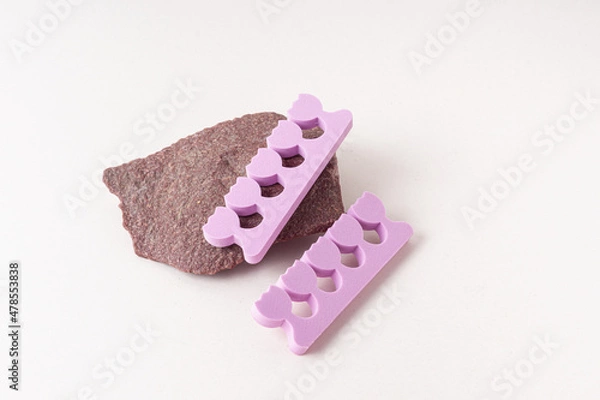 Fototapeta Purple toe dividers on stone. Tools for pedicure. Soft styrofoam. Nail painting device
